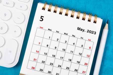 The May 2023 Monthly desk calendar for 2023 year with calculator and wooden pencil.