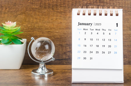 January 2023 desk calendar for 2023 year with a crystal globe against a wooden table background.の写真素材