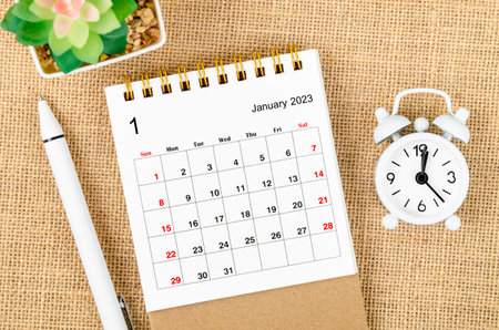 January 2023 Monthly desk calendar for the organizer to plan 2023 year with alarm clock and pen on sack background.の写真素材