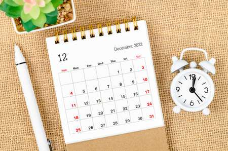 December 2022 Monthly desk calendar for the organizer to plan 2022 year with alarm clock and pen on...