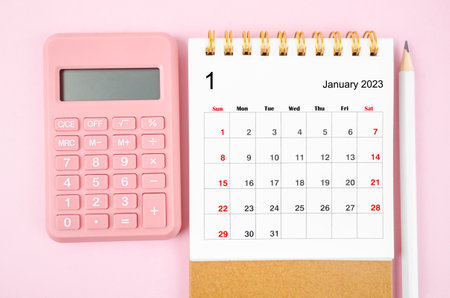 January 2023 desk calendar for 2023 year with calculator on pink color background.の写真素材