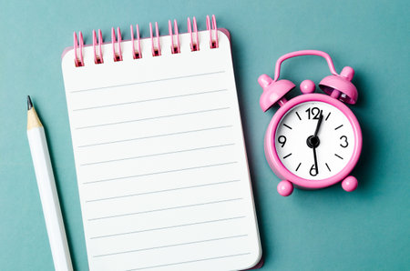 Blank open diary and Alarm clock with pencil on blue colored backgroundの写真素材