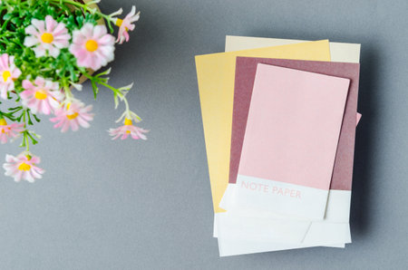 Colorful blank sticky note papers with flower on grey colour background for your text or message.