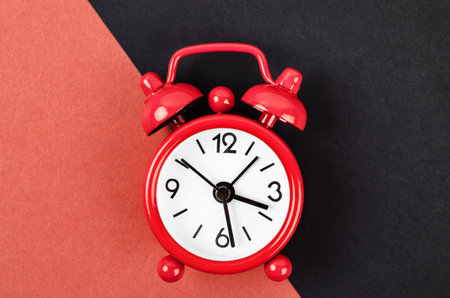 Red vintage alarm clock on red and black colour background.