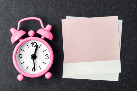 Blank reminder note and alarm clock on black background, space for text.の写真素材