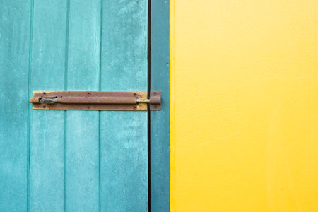 Closed padlock hangs on the yellow and blue wall doors.の写真素材