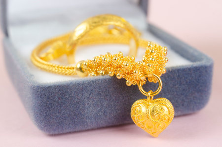 Gold necklace and heart shape pendant with ring on blue velvet box.の写真素材