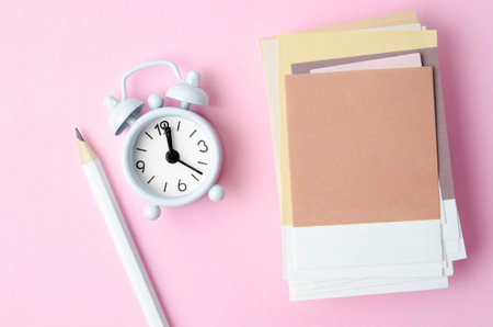 Heap of blank paper note for your text and alarm clock on pink color background.の写真素材