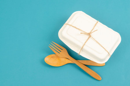 Disposable eco friendly food packaging with wooden spoon and fork on blue background.の写真素材