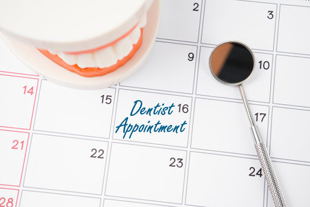 Dentist appointment writing on a calendar page and dentures model with mirror dental.の写真素材