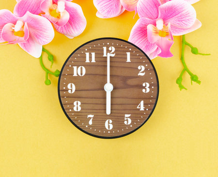 Wooden alarm clock with pick color orchid on yellow background.