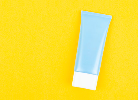 Blue squeeze bottle cosmetic tube on yellow background with copy-space.の写真素材