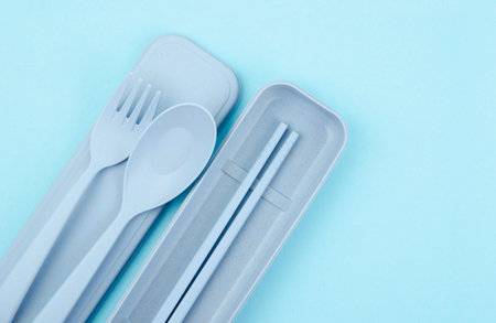 Plastic spoons, forks and chopsticks kit set on blue background.の写真素材