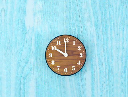 Wooden clock placed in middle of blue wooden wall.の写真素材