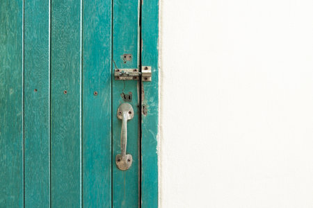 Closed padlock hangs on the green color wooden door and wall.の写真素材