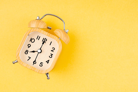 Retro wooden alarm clock on yellow color background.の写真素材