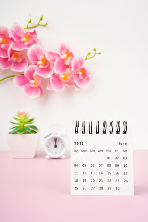 June 2023 desk calendar and pink orchid with alarm clock.の写真素材