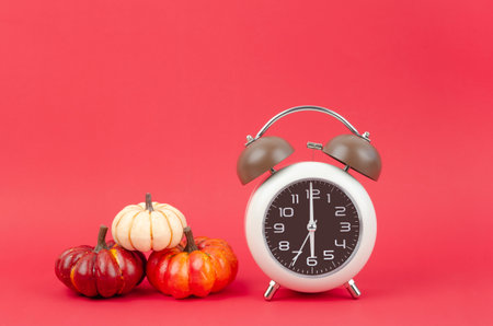 Vintage alarm clock with autumn pumpkins on red background.の写真素材