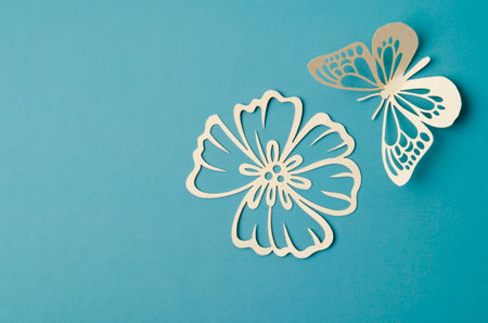 Carve of white paper butterfly and flower on a green cardboard background.の写真素材