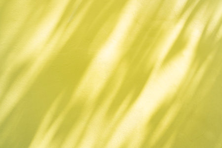 Natural shadow overlay on yellow colored grunge wall concrete texture background. Textures Light reflection from the window.の写真素材