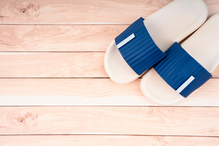 White and blue color rubber slipper shoes on wooden floor with copy space. Summer holiday vacation concept.の写真素材