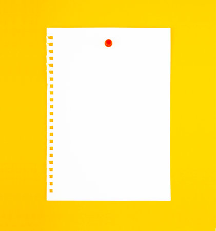 Blank white torn paper note with push pin on yellow board background.
