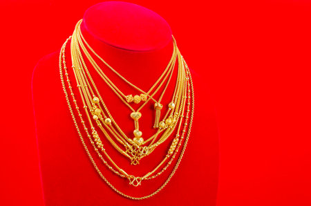Necklace display stand with gold necklace on red Velvet fabric background.の写真素材