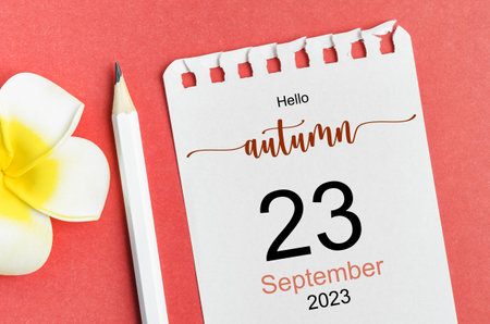Hello autumn on 23rd September 2023 calendar and pen with flower on red background.の写真素材