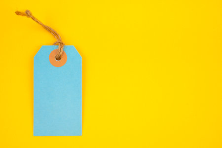 Blue color blank price tag on yellow background. Great for use as a price tag, gift tag, sale tag.の写真素材