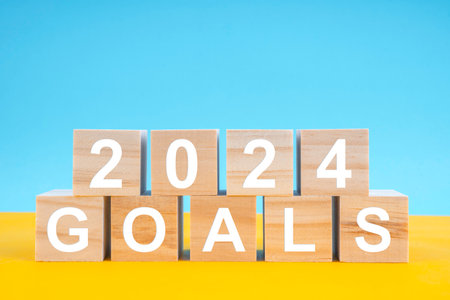 Wooden cubes 2024 GOALS on yellow and blue background. Planning and goals concepts on 2024 year.
