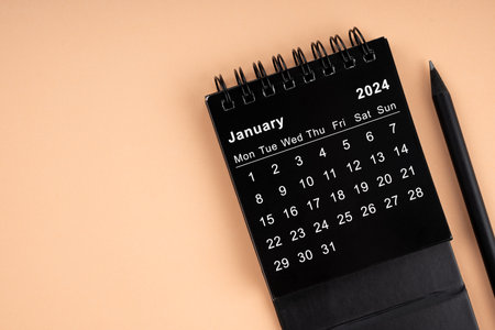 January 2024 Black spiral desktop calendar and wooden pencil on yellow background.の写真素材