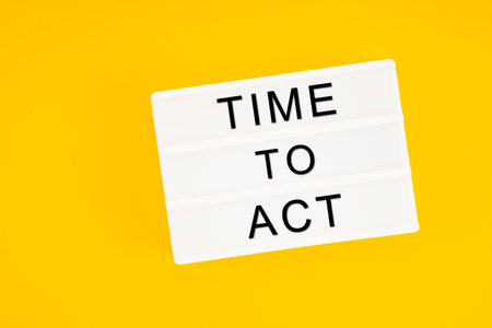 Time to act text on white lightbox sitting on yellow background. Horizontal composition with copy space.の写真素材