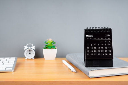 March 2024 black color desk calendar on wooden table with diary.の写真素材