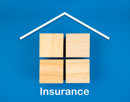 Real Estate icons on wooden blocks on blue background. Home Insurance concepts.の写真素材