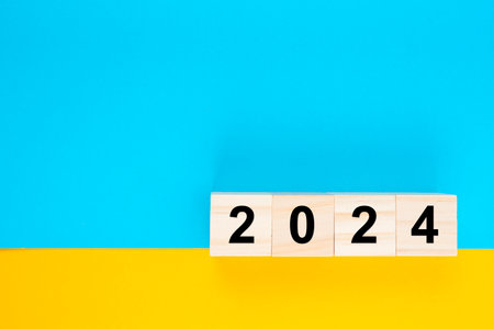 Wooden cube block 2024 number on blue and yellow background.