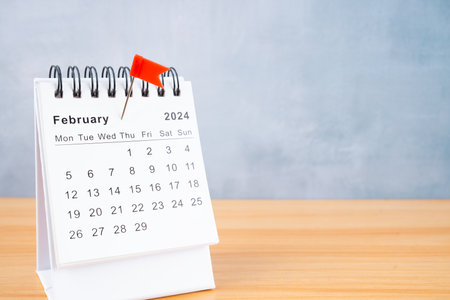 February 2024 calendar and red push pin on wooden table.の写真素材