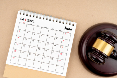 Desk calendar for June 2024 and judge's gavel on brown background.の写真素材