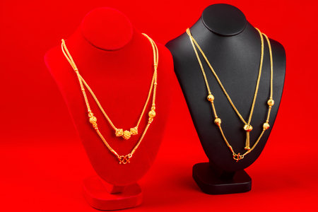 Accessory and gold jewelry necklace display stand with gold necklace on red Velvet fabric.の写真素材