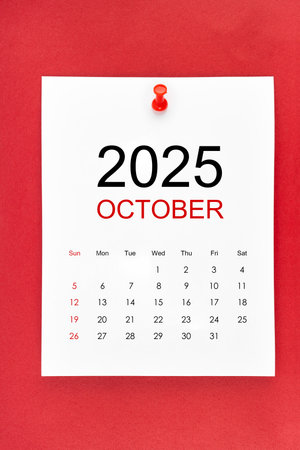 October 2025 calendar page with push pin on red color background.の写真素材