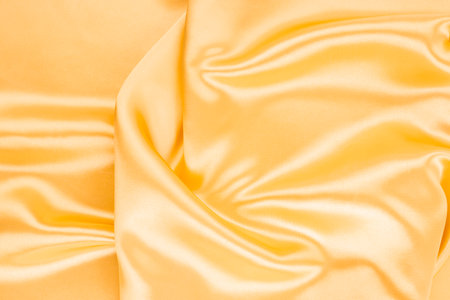 Yellow silk satin. Draped fabric. golden color. Luxury background. Space for designの写真素材