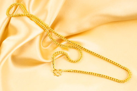 A Gold Necklace on gold color silk background.の写真素材