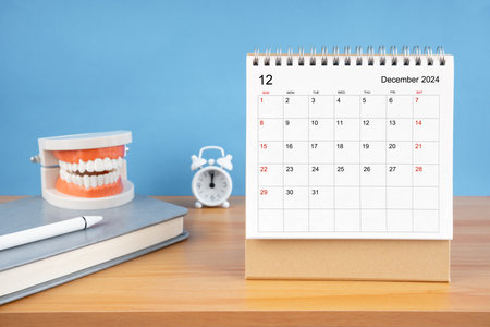 December monthly desk calendar for 2024 year and model dentures on the table. Dental health concepts.の写真素材