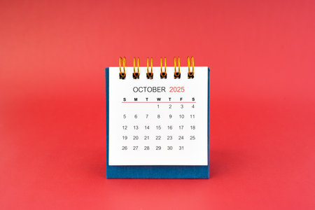October 2025 white desk calendar on red color background.の写真素材