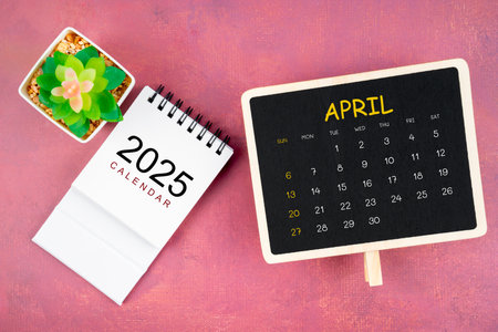 Calendar for April 2025 in black chalkboard on red wooden background.の写真素材