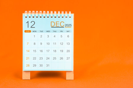 December 2025 desk calendar stand on orange color textile background.の写真素材