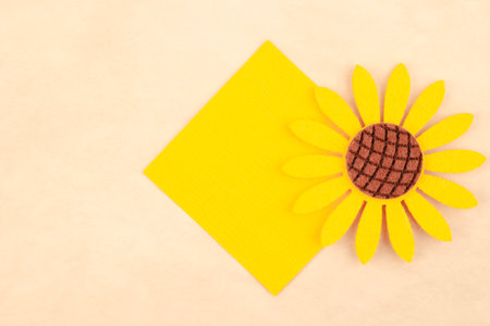 Yellow blank paper note with sunflowers design on brown background.の写真素材
