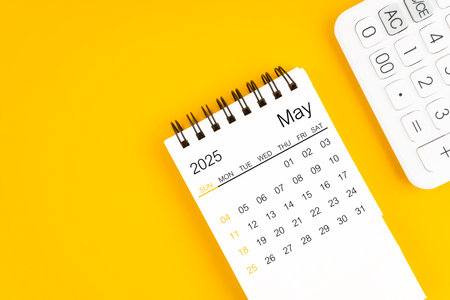 May 2025 calendar and calculator on yellow background, Flat lay.の写真素材