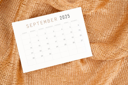 September 2025 calendar card on golden color textile background.の写真素材