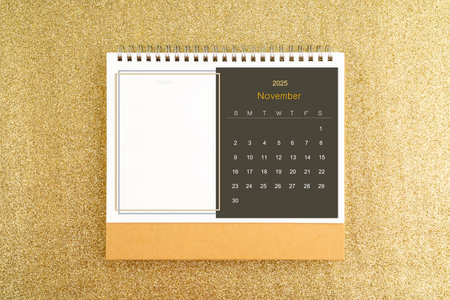 Desk calendar for November 2025 on gold color glitter background.の写真素材