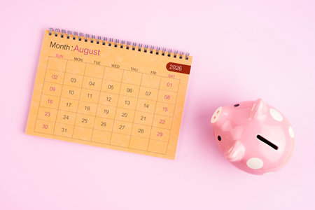 Brown desk calendar for August 2026 and pink piggy bank.の写真素材